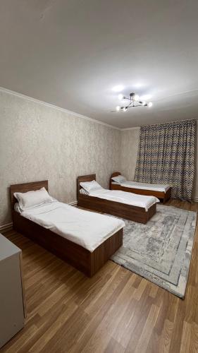 two beds in a room with wooden floors at DARAI guest house Hostel Turkistan in Türkistan