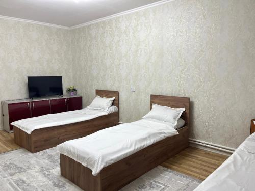 a room with two beds and a tv on the wall at DARAI guest house Hostel Turkistan in Türkistan