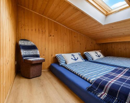 a room with a bed and a chair in a cabin at Domki Boja in Swarzewo