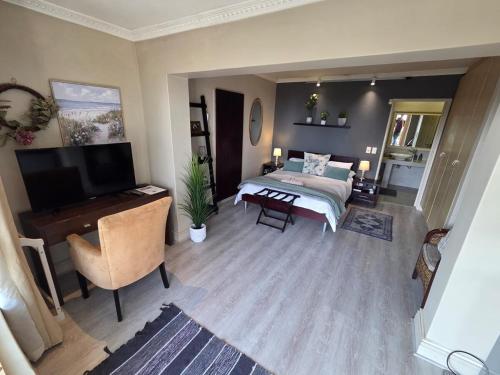 a bedroom with a bed and a desk and a television at Palm Zicht in Cape Town