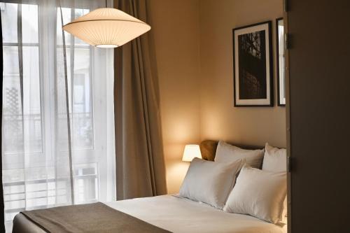 a bedroom with a bed with a window and a lamp at Hotel Local 101 Beaurepaire in Paris