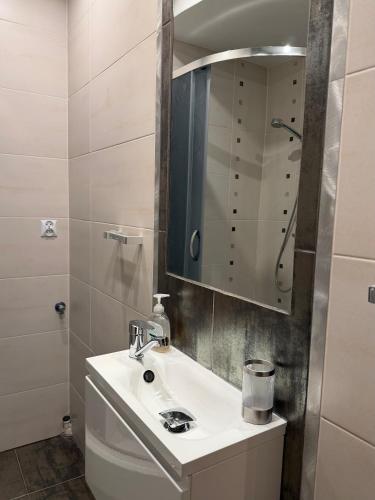a white bathroom with a sink and a mirror at Przytulna Kawalerka Łeba in Łeba
