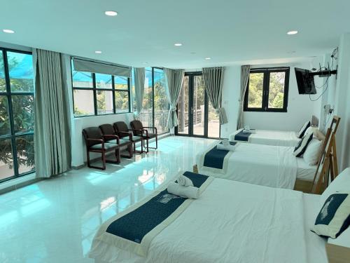 a hotel room with two beds and chairs and windows at Mango Villa Long Hải Beach in Long Hai