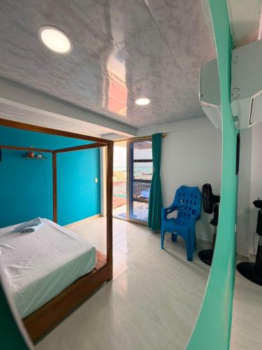 a bedroom with a bed and a blue chair at El Gran Jeronimo Hostal Rincon del Mar in Rincón