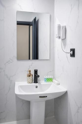 a white bathroom with a sink and a mirror at Airport Garden hotel in Pʼarakʼar