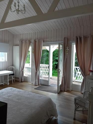 a bedroom with a bed and sliding glass doors at Le Charme au Fil de l'eau in Neslette