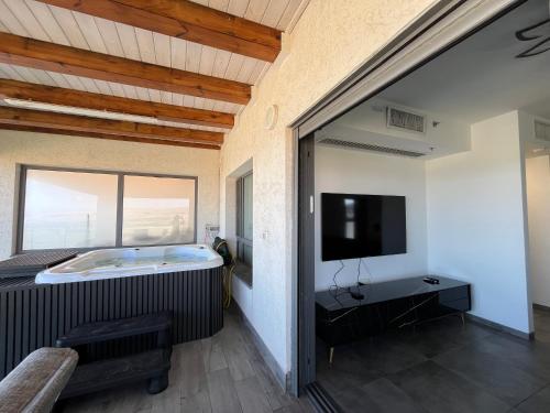 a room with a tub and a tv and a window at סוויטת נוף התכלת in Migdal
