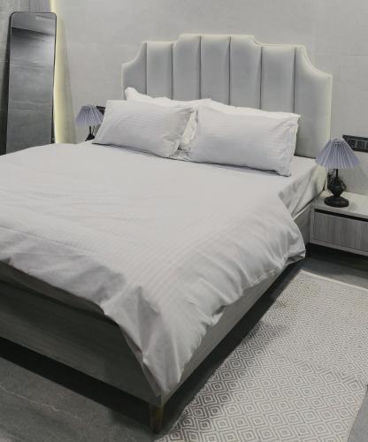 a large bed with white sheets and pillows at Grey Courtyard Entire Studio Taj Mahal Parking 3KM in Agra