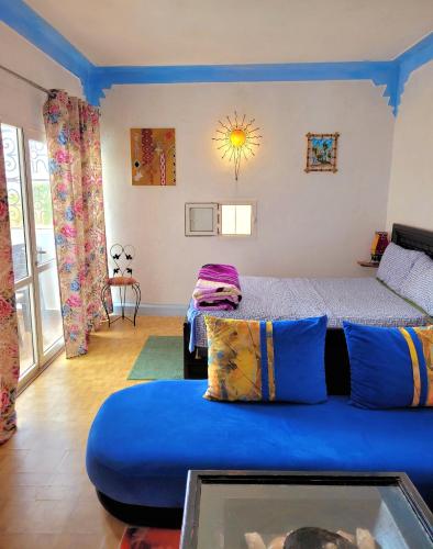 a living room with a blue couch and a bed at Maison de la Lagune in Oualidia