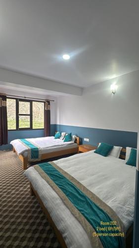 a bedroom with two beds and a window at Hotel Marpha Comfort And Restaurant in Tukucha