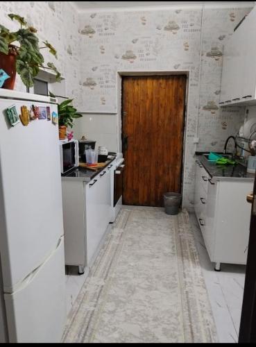 a kitchen with white appliances and a wooden door at Keremet house in Barskoon