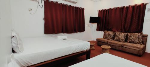 a room with two beds and a chair and red curtains at Nature Nest In in Auroville