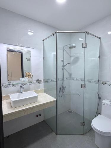a bathroom with a glass shower and a sink at Mango Villa Long Hải Beach in Long Hai