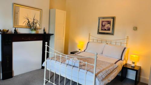 a bedroom with a bed with two lamps and a fireplace at Private Ensuite Room with Bay Window, Free Parking and Fast WiFi in Sheffield