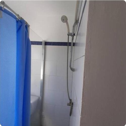 a bathroom with a shower with a blue shower curtain at Hostel WAIVING MILL in Oranjestad
