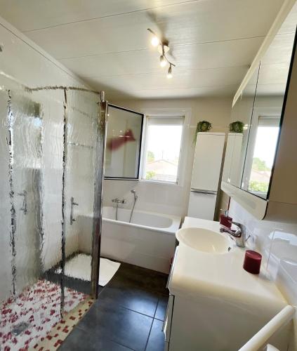 a bathroom with a tub and a sink and a shower at Chambres d'hôtes La Rose Des Sables in Les Herbiers