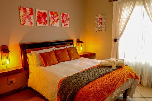 a bedroom with a bed with orange pillows and a window at Skilpadvlei Cottage and Studio's in Velddrif