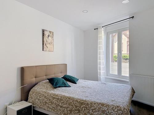 a white bedroom with a bed and a window at EM LIFE COLMAR in Colmar