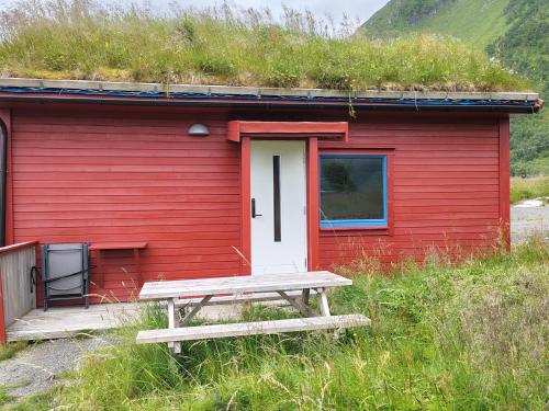 a red house with a bench in front of it at Rystad Lofoten Camping in Rystad