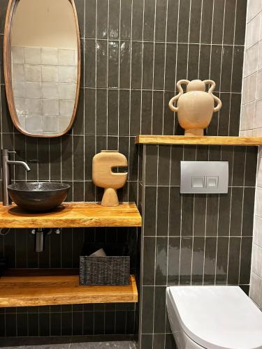 a black tiled bathroom with a sink and a mirror at De Kustwacht in Warmenhuizen