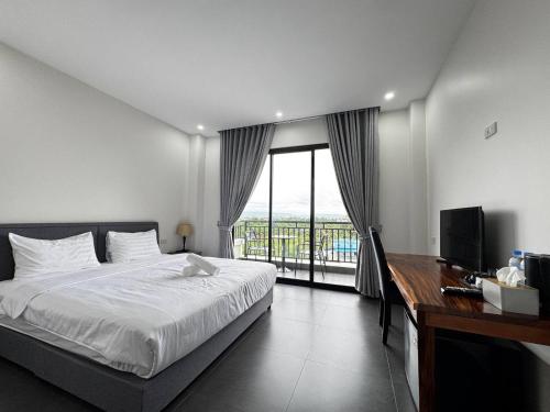 a bedroom with a bed and a desk and a window at De Zee Hotel in Koh Kong