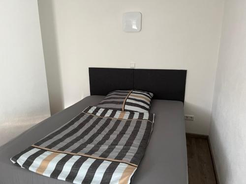 a bed with a black and white striped blanket on it at Ferienwohnung Krayenbergblick 1 in Bad Salzungen