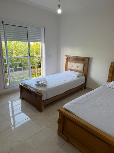 a bedroom with two beds and a large window at Appartement avec piscine, résidence assadaka in Saïdia