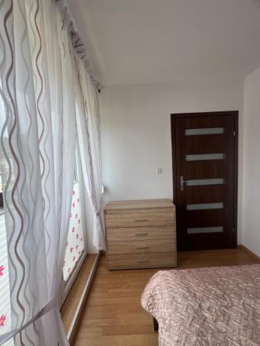 a bedroom with a bed and a dresser and a door at Apartament Łeba in Żarnowska