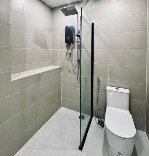 a bathroom with a toilet and a glass shower stall at De Zee Hotel in Koh Kong