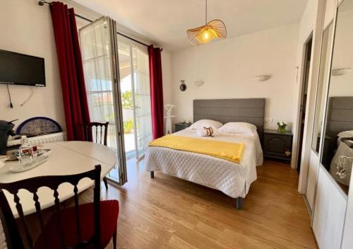 a bedroom with a bed and a table in it at Chambres d'hôtes La Rose Des Sables in Les Herbiers