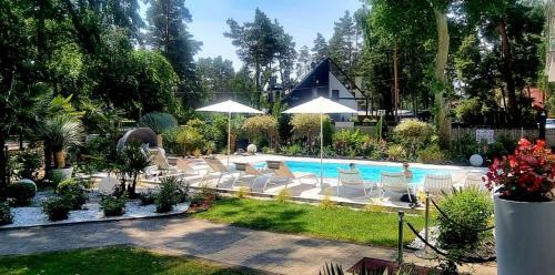 a pool with chairs and umbrellas in a yard at Majestique in Pobierowo