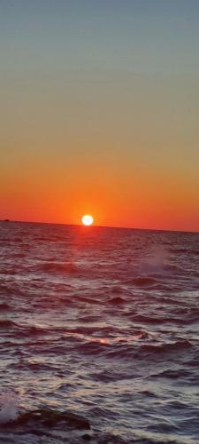 a sunset over the ocean with the sun in the sky at KENZY Apartment in Alexandria