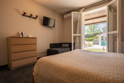 a bedroom with a bed and a chair and a window at Country Resort Le Due Ruote in Alberese
