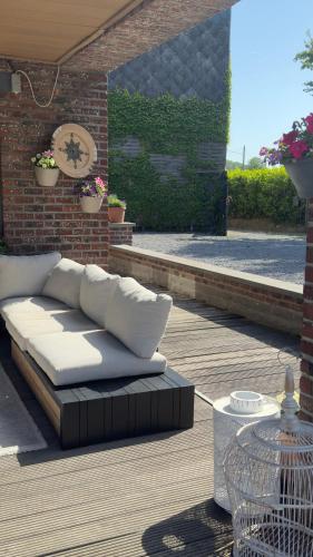 a couch sitting on a patio with a brick wall at Countryside house by Pairi Daiza in Silly