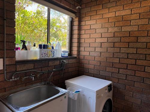 a kitchen with a sink and a washing machine at 4BR big family house with huge pool in Brisbane