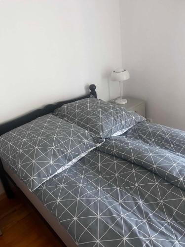 a bed with a black and white comforter in a bedroom at Domek Augustów Monika in Augustów