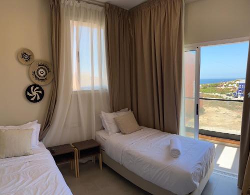 a hotel room with two beds and a large window at Imsouane Harmony in Imsouane