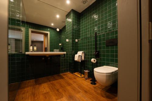 a green tiled bathroom with a toilet and a sink at Santo Thyrso Hotel in Santo Tirso