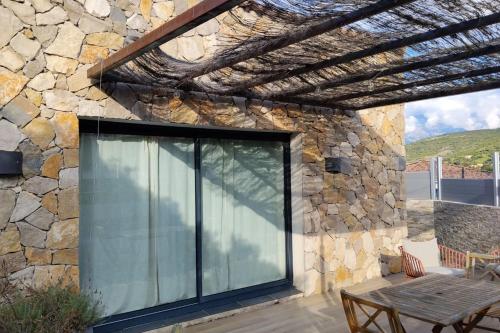 a patio with a glass door on a stone wall at Casa Sol location de vacances indépendante à Calvi moins de 2km plage in Calvi