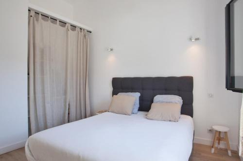 a bedroom with a white bed with two pillows at Casa Sol location de vacances indépendante à Calvi moins de 2km plage in Calvi