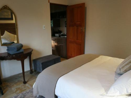 a bedroom with a bed and a table with a mirror at Martin Villa in Somerset West