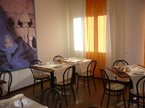 una sala da pranzo con tavoli, sedie e un dipinto di Hotel Sport a Portogruaro