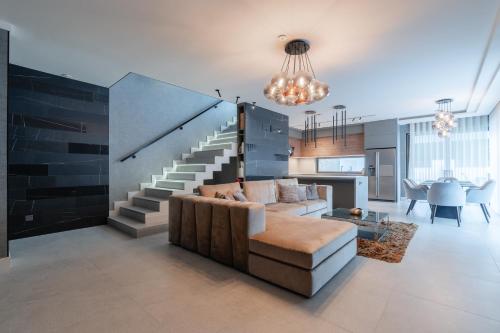 a living room with a couch and a staircase at Villa Glam Wellness & Spa Retreat in Mogyoród