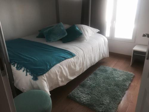 a bed in a bedroom with a window and a rug at La maison spacieuse et confortable in Deauville
