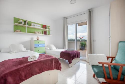 a bedroom with two beds and a chair and a window at Casa ELPI in Guardiola
