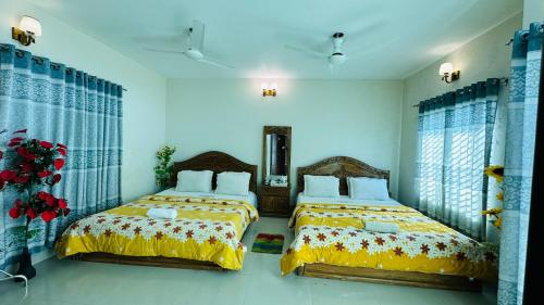 two beds in a bedroom with yellow bedding at Hotel Nice Look Kuakata in Kuākāta