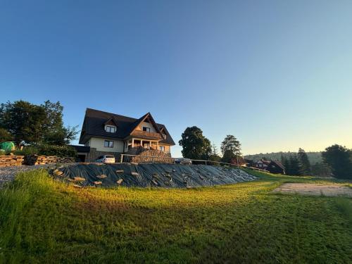 a house on top of a hill with a grass field at Villa Szarotka in Dzianisz