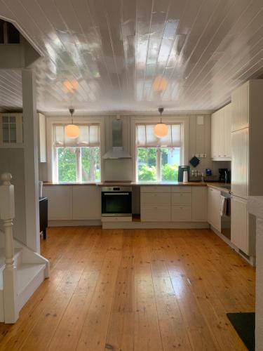 a large kitchen with white cabinets and a wooden floor at Mølleråsen Apartment in Sandefjord