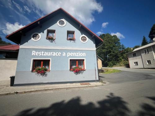 a white building with flowers in the windows at Penzion U Zemánků in Jablonec nad Jizerou