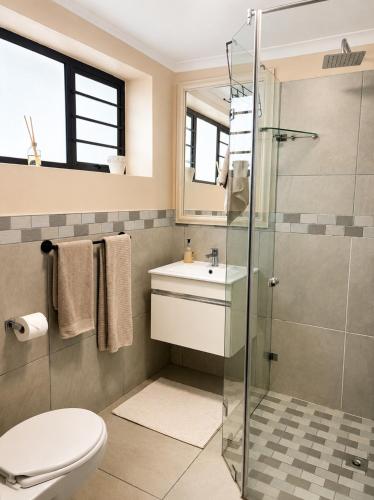 a bathroom with a shower and a toilet and a sink at Oceanfront Escape Beach House in Strand
